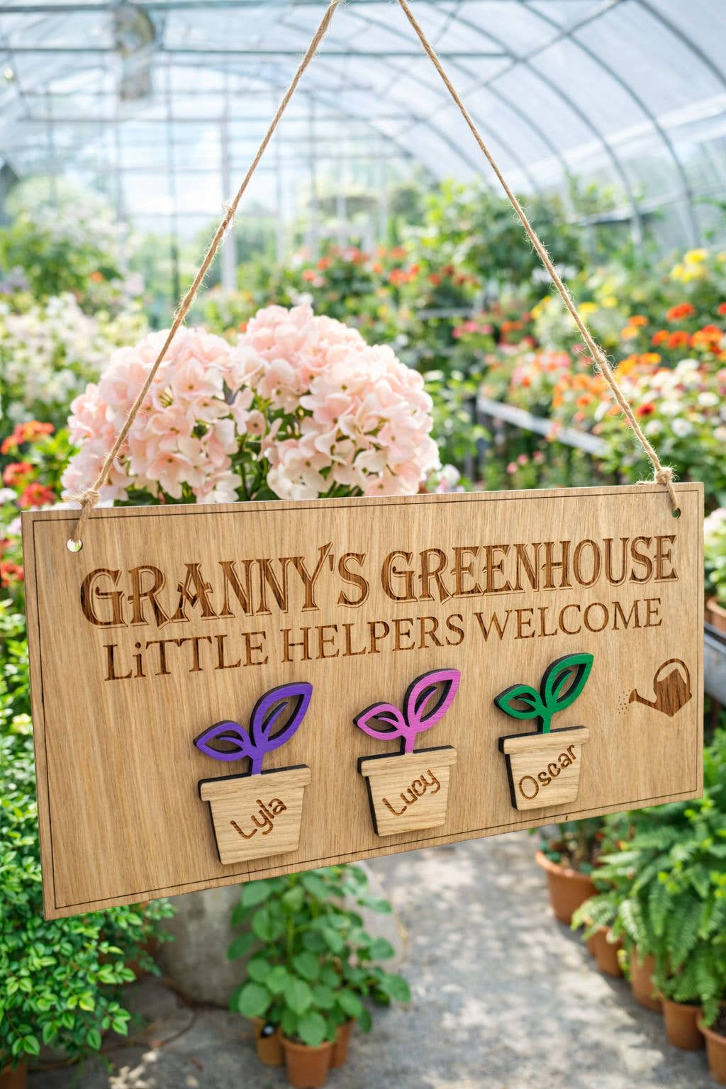 Personalised Grandad’s Greenhouse wooden sign with little helpers welcome text and Theo plant pot design hanging in a FLOWER illed greenhouse.
